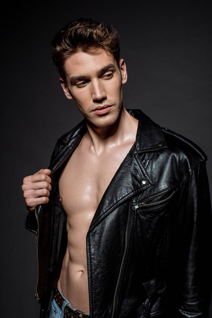 сексуальний молодий чоловік з м'язистим торсом в куртці для байкерів на чорному тлі
 - Фото, зображення