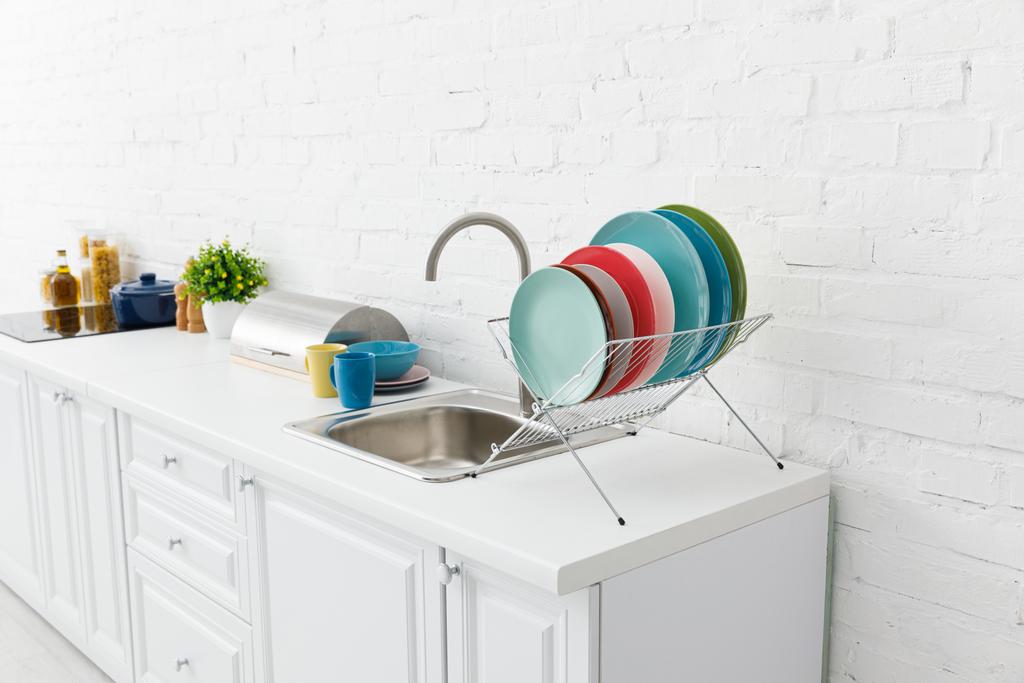 современный белый интерьер кухни с посудой возле кирпичной стены
 - Фото, изображение
