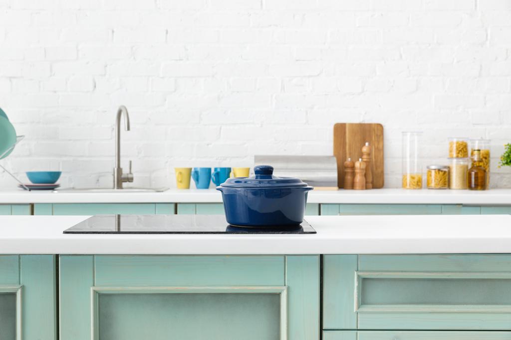 selective focus of modern white and turquoise kitchen interior with pot on electric induction cooktop - Photo, Image
