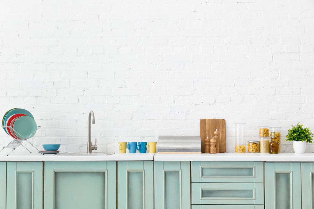 moderní bílý a tyrkysový kuchyňský interiér s nádobím u cihlové zdi - Fotografie, Obrázek