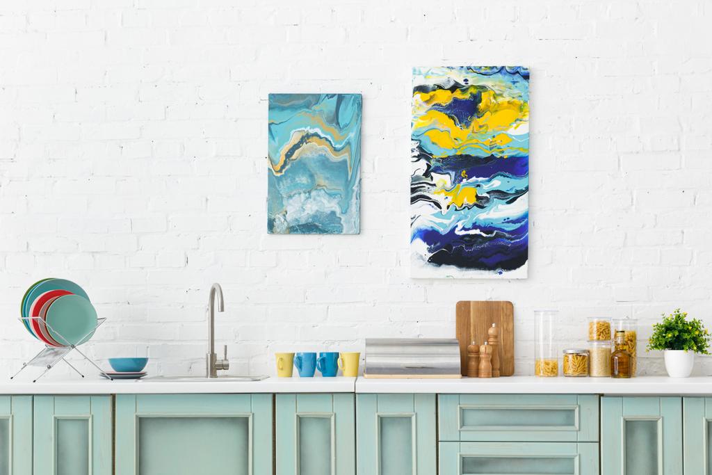 сучасний біло- бірюзовий кухонний інтер'єр з кухонним посудом та абстрактними картинами на цегляній стіні
 - Фото, зображення