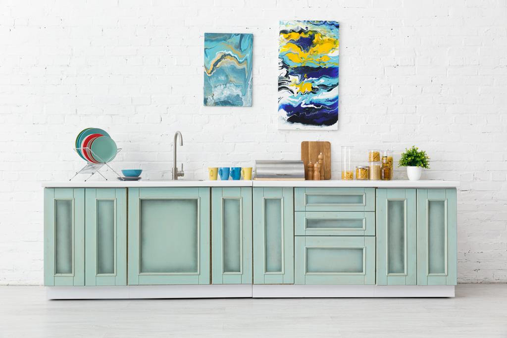 台所用品とレンガの壁に抽象絵画と近代的な白とターコイズキッチンのインテリア - 写真・画像