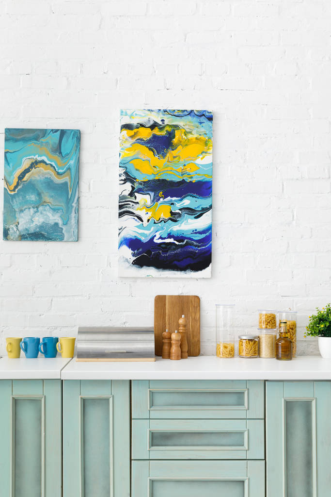 intérieur de cuisine moderne blanc et turquoise avec ustensiles de cuisine et peintures abstraites sur mur de briques
 - Photo, image