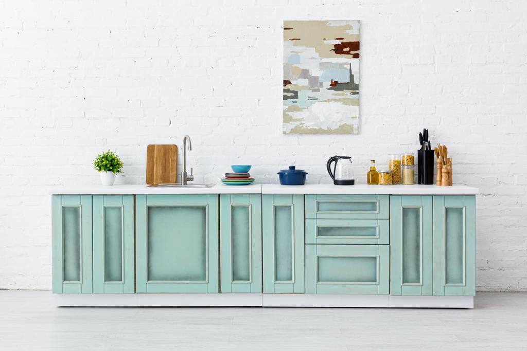 branco e turquesa cozinha interior com utensílios de cozinha e pintura abstrata na parede de tijolo
 - Foto, Imagem