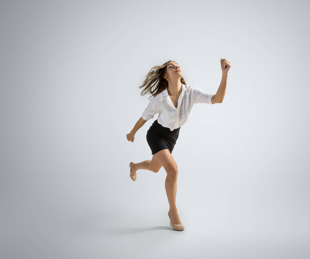 Mulher caucasiana em roupas de escritório correndo isolado em fundo estúdio cinza
 - Foto, Imagem