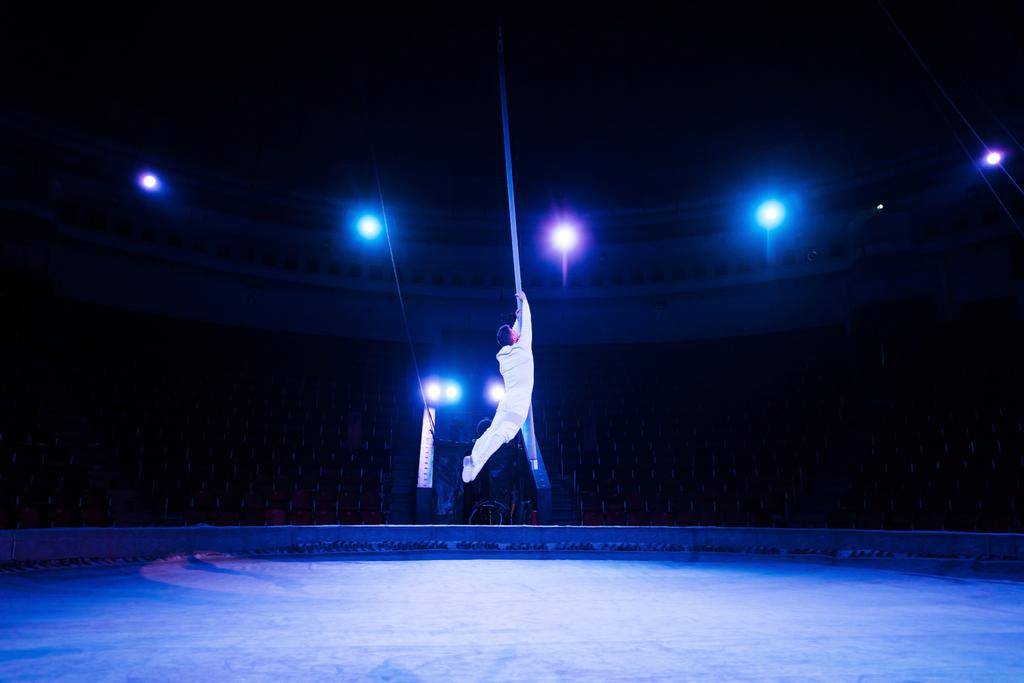 blue light near acrobat performing in arena of circus  - Photo, Image