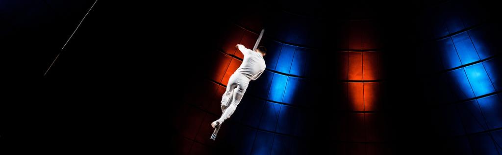 panoramic shot of acrobat performing on pole in arena of circus  - Photo, Image