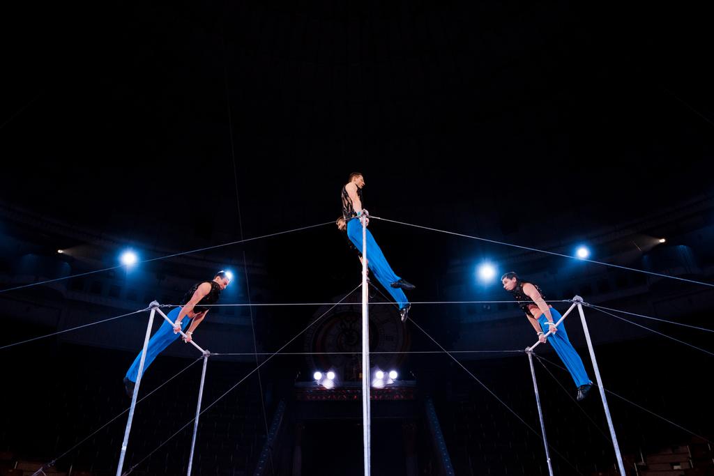 low angle view of gymnasts performing on horizontal bars in circus   - Photo, Image