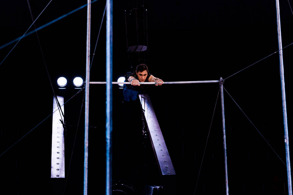 acrobat atlético realizando en barras horizontales en arena de circo
   - Foto, imagen