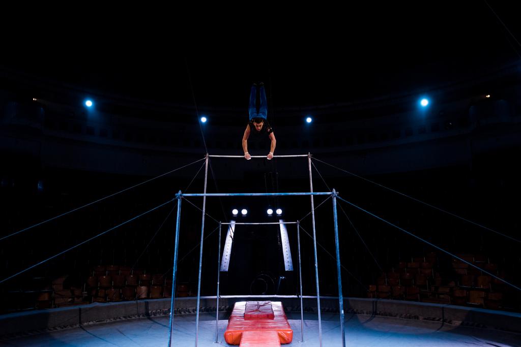 komea ja urheilullinen voimistelija suorittaa vaakasuorassa baareissa areenalla sirkus
   - Valokuva, kuva