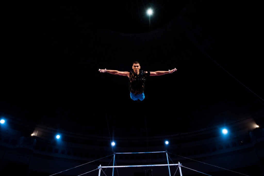 спортивний гімнаст з простягнутими руками на арені цирку
   - Фото, зображення