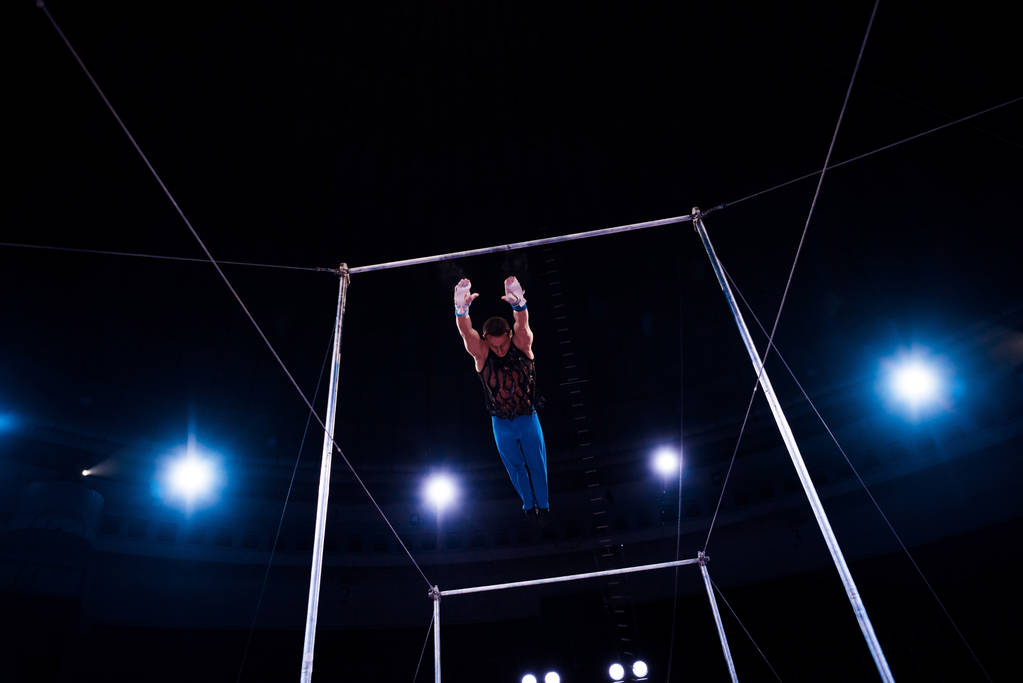 Sirk arenasında yatay barlarda gösteri yaparken atlayan atletizm sporcusu   - Fotoğraf, Görsel