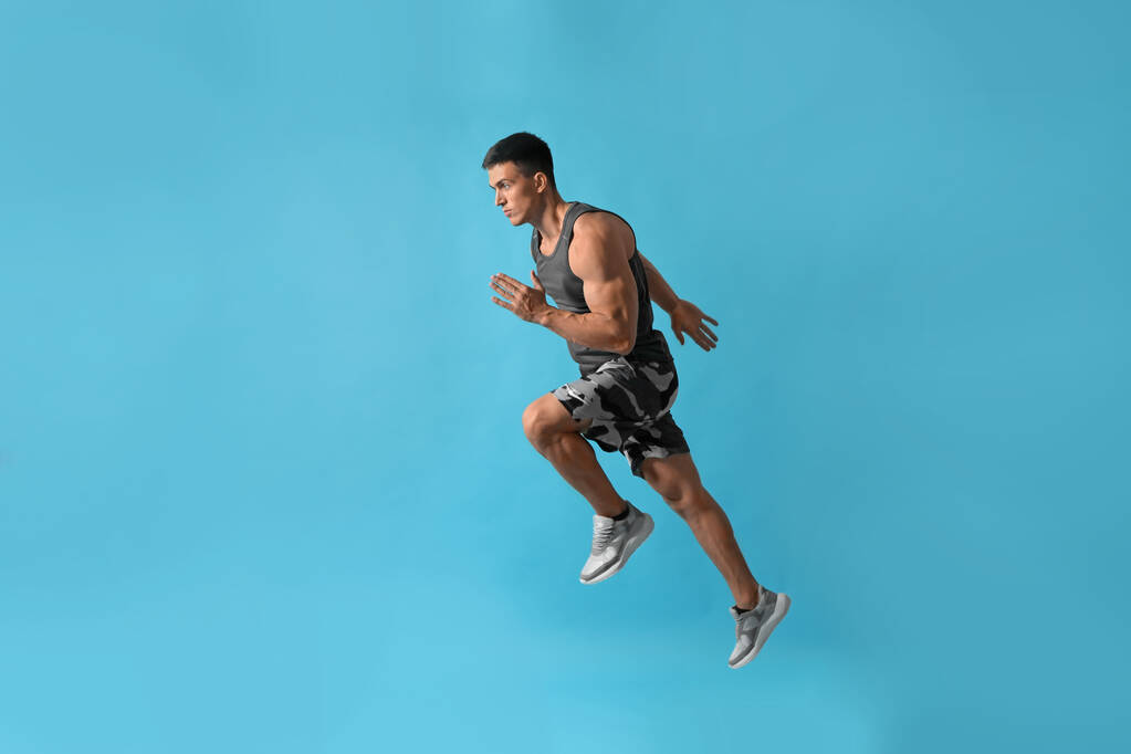 athletischer junger Mann läuft auf hellblauem Hintergrund, Seitenansicht - Foto, Bild