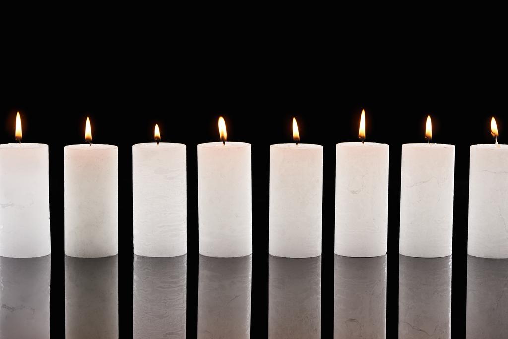 burning white candles glowing in line isolated on black - Photo, Image
