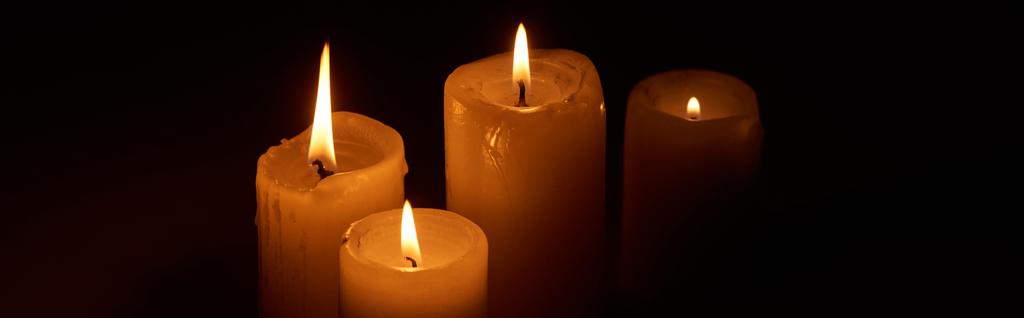 brennende Kerzen, die in der Dunkelheit auf schwarzem Hintergrund glühen, Panoramaaufnahme - Foto, Bild