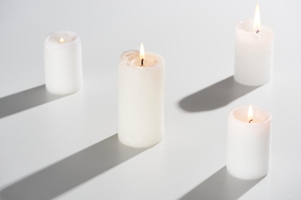 brennende Kerzen auf weißem Hintergrund mit Schatten - Foto, Bild