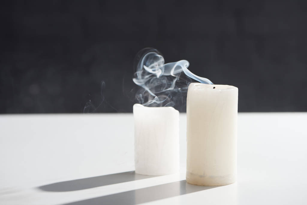 σβησμένα λευκά κεριά με καπνό σε μαύρο φόντο - Φωτογραφία, εικόνα