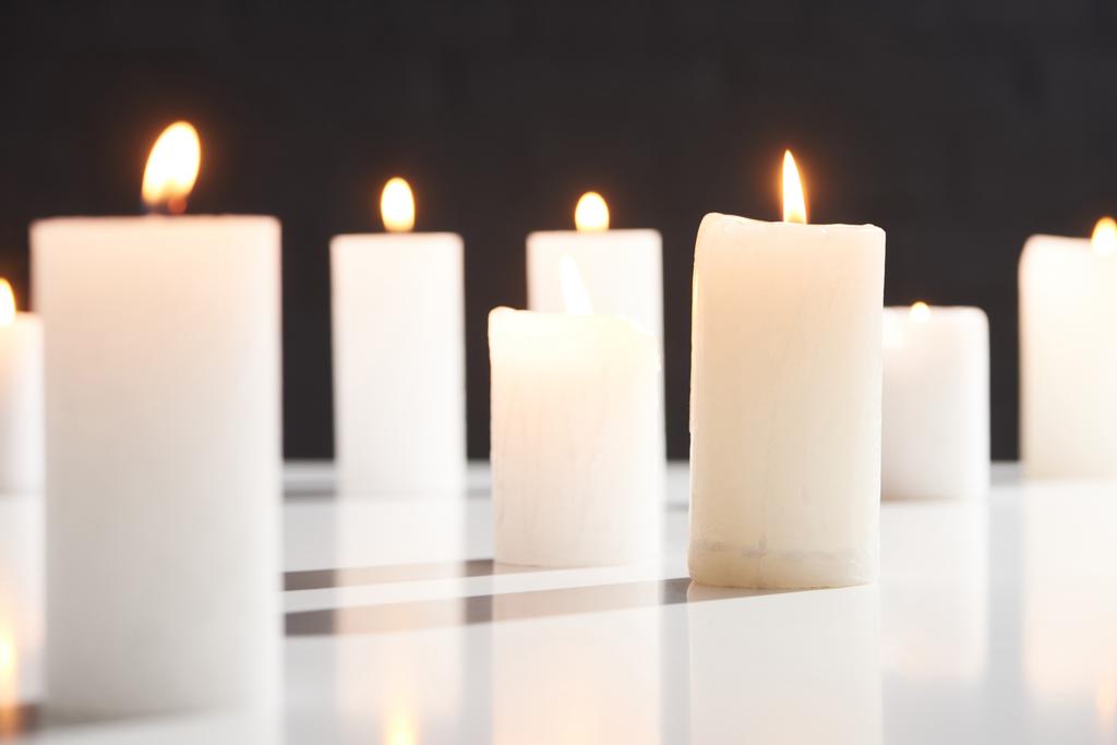 enfoque selectivo de la quema de velas blancas en la superficie blanca brillante aislado en negro
 - Foto, imagen