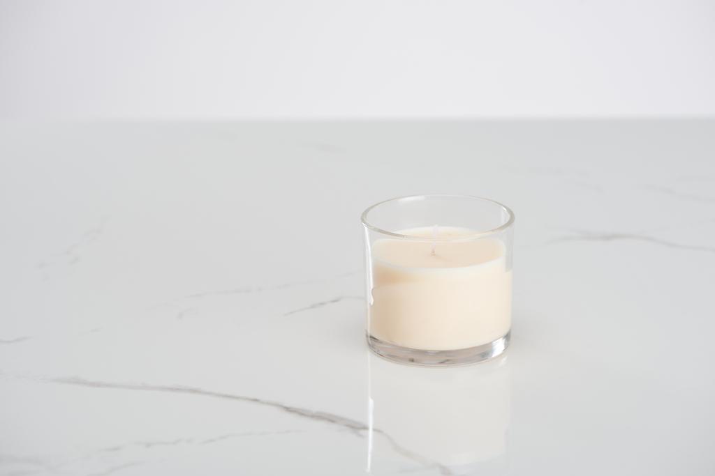 witte kaars in glas op marmeren wit oppervlak - Foto, afbeelding