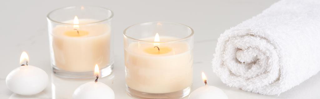 αναμμένα λευκά κεριά σε γυαλί και τυλιγμένη πετσέτα σε μαρμάρινη λευκή επιφάνεια, πανοραμική λήψη - Φωτογραφία, εικόνα