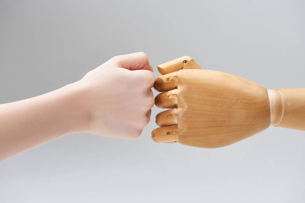 Обрізаний вигляд рук жінки і дерев'яна лялька робить кулак зсувом ізольованим на сірому
 - Фото, зображення