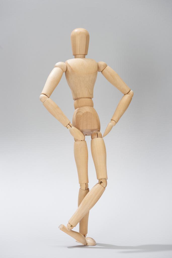 Muñeca de madera con las manos en las caderas sobre fondo gris
 - Foto, imagen
