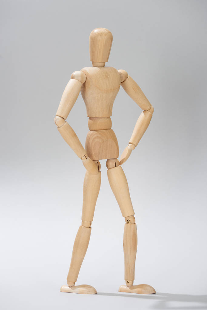 Drewniana marionetka z akimbo pozą na szarym tle - Zdjęcie, obraz