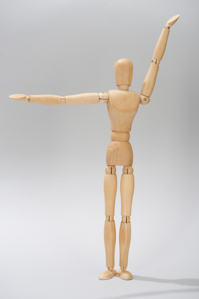Marionnette en bois avec les mains levées sur fond gris
 - Photo, image