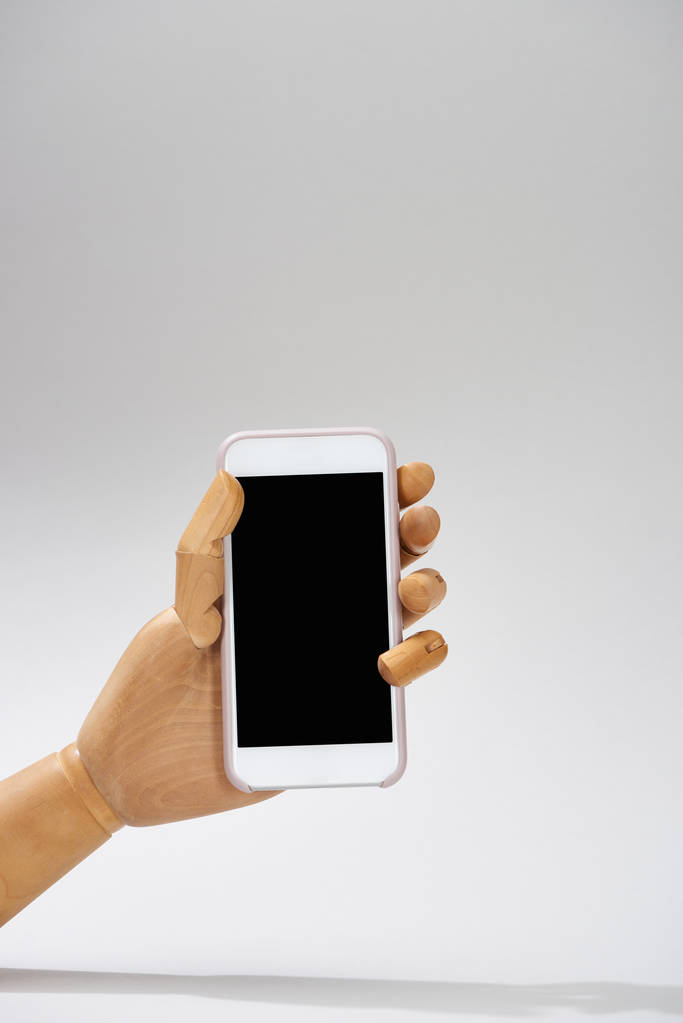 Mão de boneca de madeira com smartphone em fundo cinza
 - Foto, Imagem