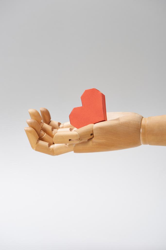 Hand of wooden puppet with heart shaped paper isolated on grey - Photo, Image