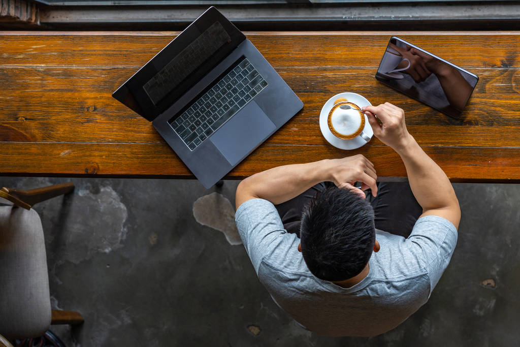 Ázsiai szabadúszó dolgozik laptop és élvezi a forró cappuccino - Fotó, kép