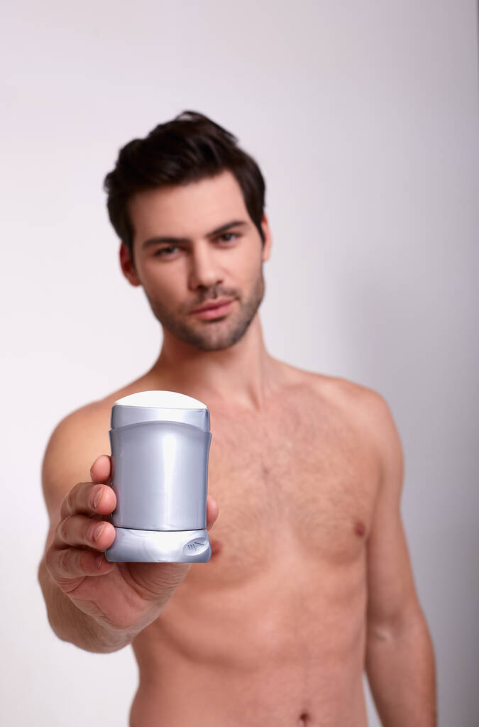 Pystysuora ampua viileä paljas kaveri deodorantti oikeassa kädessä
 - Valokuva, kuva