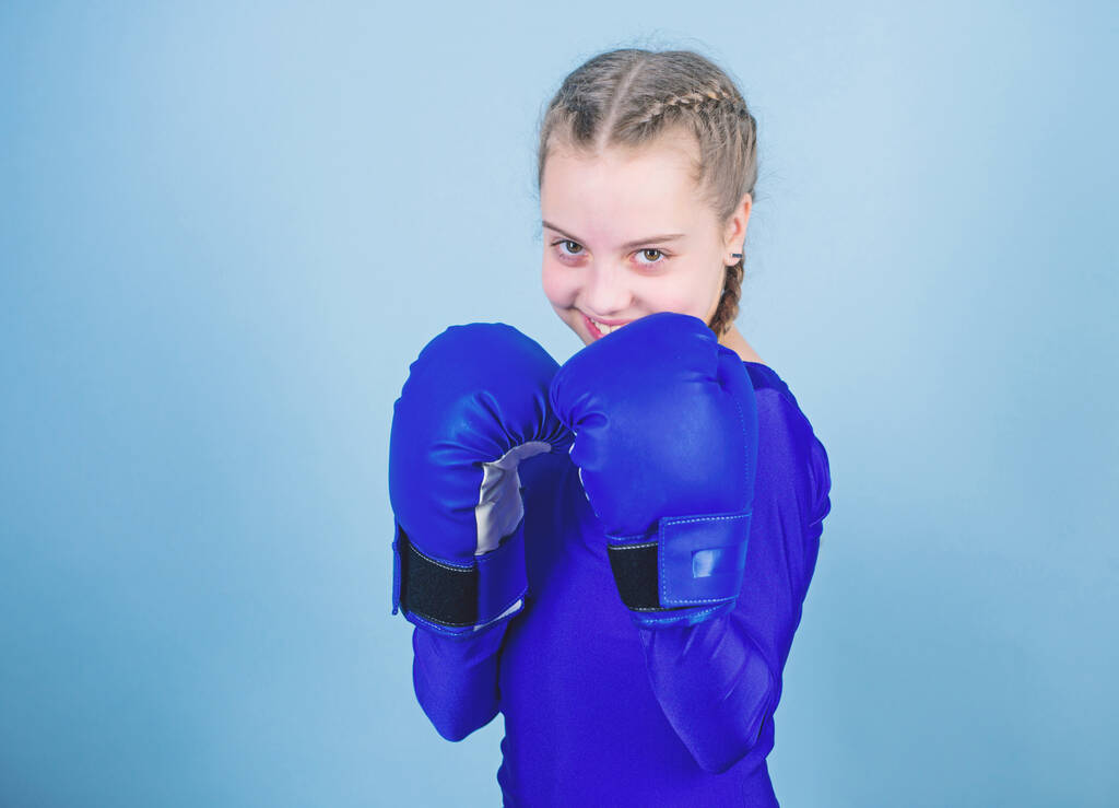 Emelkedik a nők ökölvívók. Női bokszoló változás hozzáállás a sporton belül. Feminizmus fogalmát. Nagy erővel jön nagy felelősség. Boxer gyermek bokszkesztyűben. Lány aranyos bokszoló kék háttér - Fotó, kép