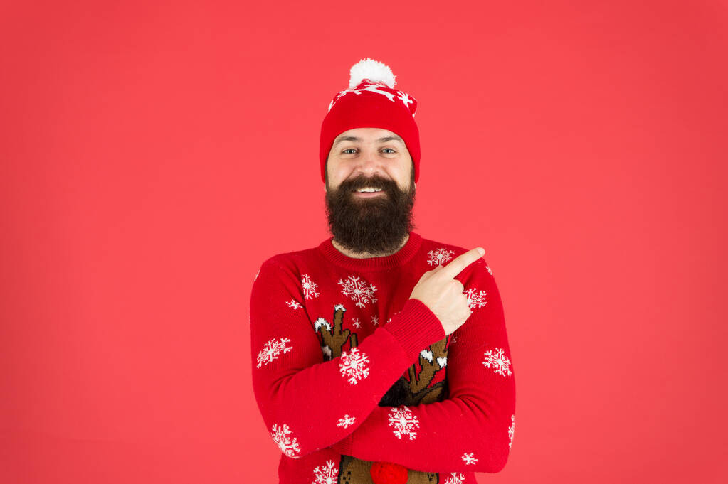 зрілий бородатий чоловік оленячий светр. жорстокий хіпстер на в'язаному капелюсі червоний фон. носіть різдвяний настрій. в'язаний одяг чоловічої моди. смішний чоловік, який вказує пальцем. досі вірять у Санта Клауса
 - Фото, зображення