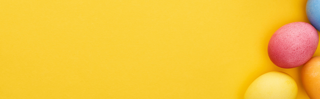 πάνω άποψη του πολύχρωμα βαμμένα πασχαλινά αυγά σε κίτρινο φόντο με αντίγραφο χώρου, πανοραμική λήψη - Φωτογραφία, εικόνα