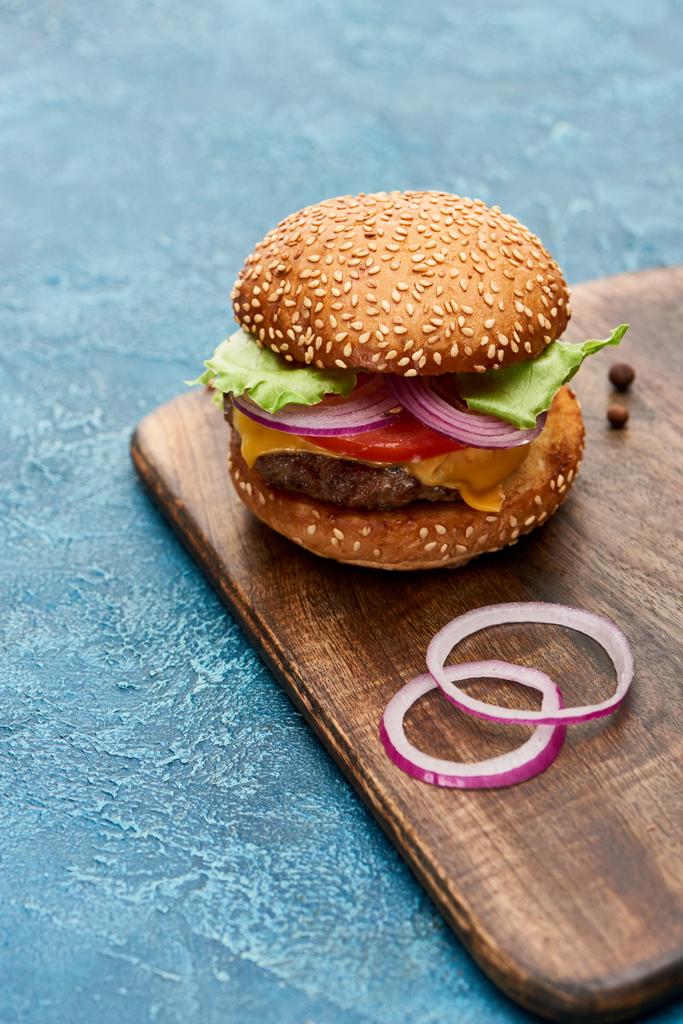 νόστιμο cheeseburger σε ξύλινο πίνακα σε μπλε υφή επιφάνεια - Φωτογραφία, εικόνα
