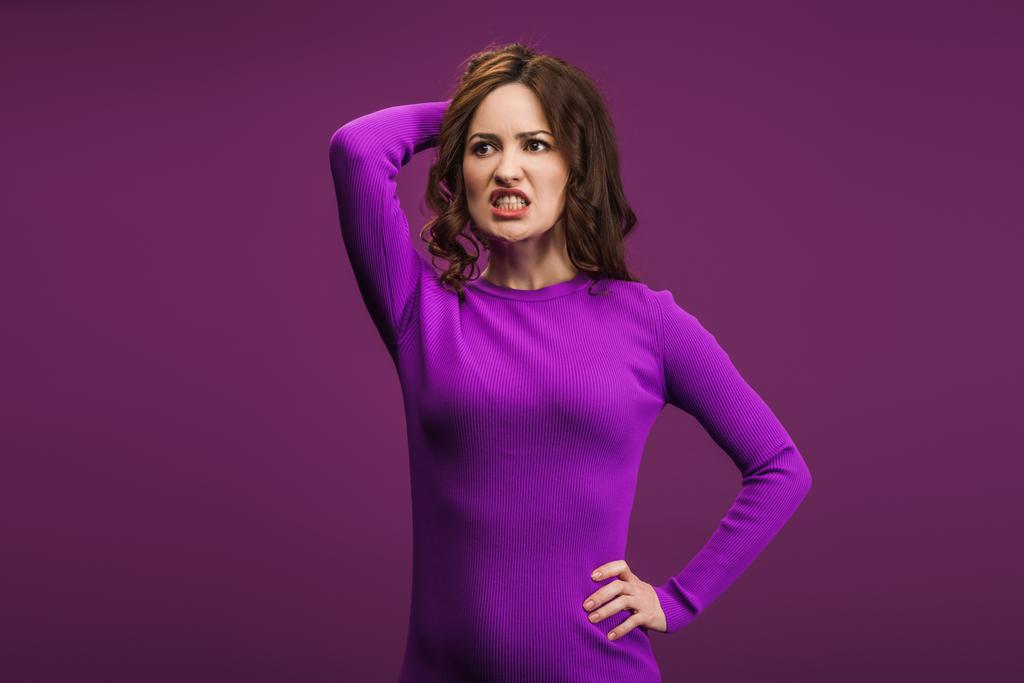 angry woman standing with hand on hip and touching head on purple background - Photo, Image
