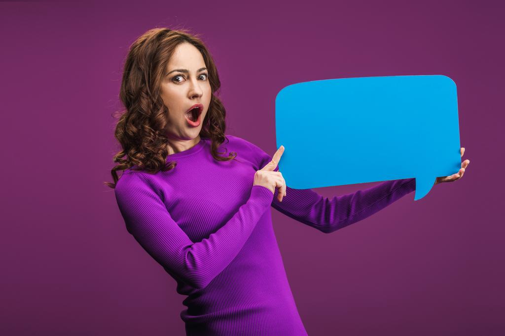 шокована жінка тримає мовну бульбашку на фіолетовому фоні
 - Фото, зображення