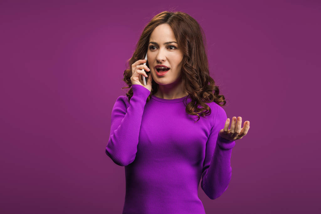 Şaşırmış bir kadın mor arka planda akıllı telefondan konuşuyor. - Fotoğraf, Görsel