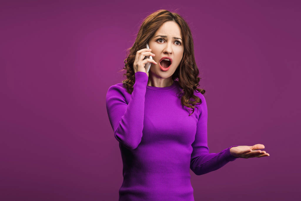 dühös nő sikoltozik, miközben beszél okostelefon lila háttér - Fotó, kép