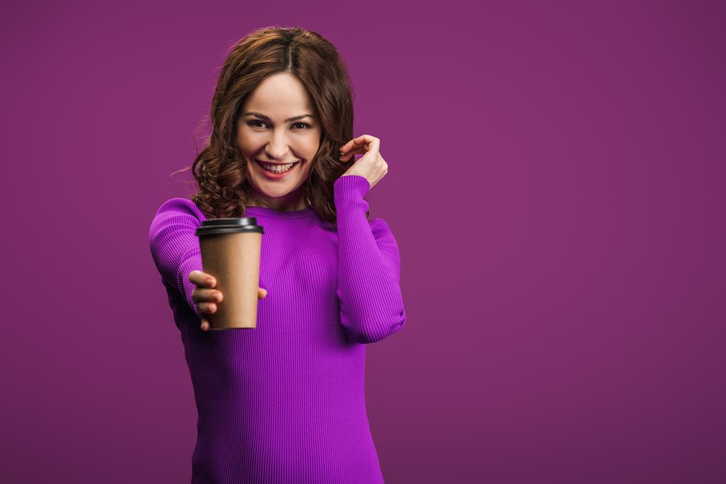 紫色の背景にコーヒーを飲みながらカメラで微笑む可愛い女の子 - 写真・画像