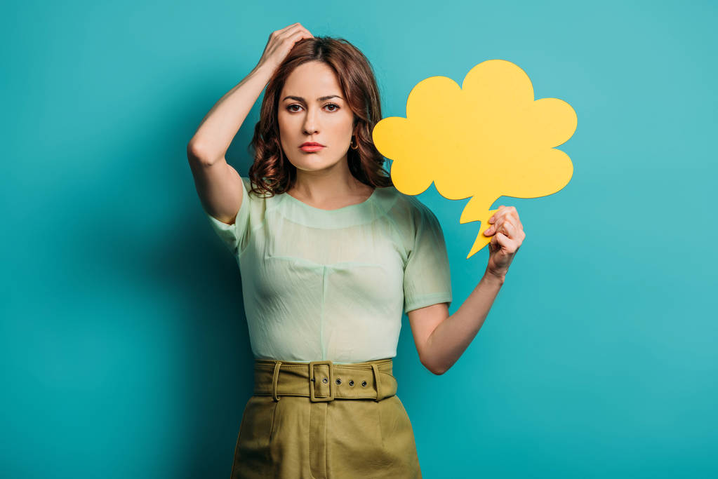 thoughtful woman touching head while holding thought bubble on blue background - Photo, Image