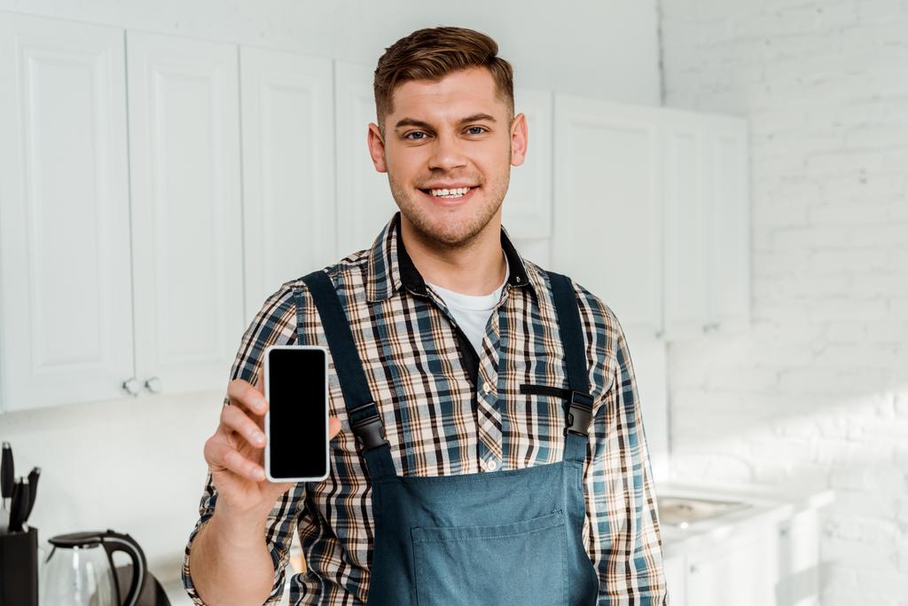 cheerful installer holding smartphone with blank screen  - Photo, Image