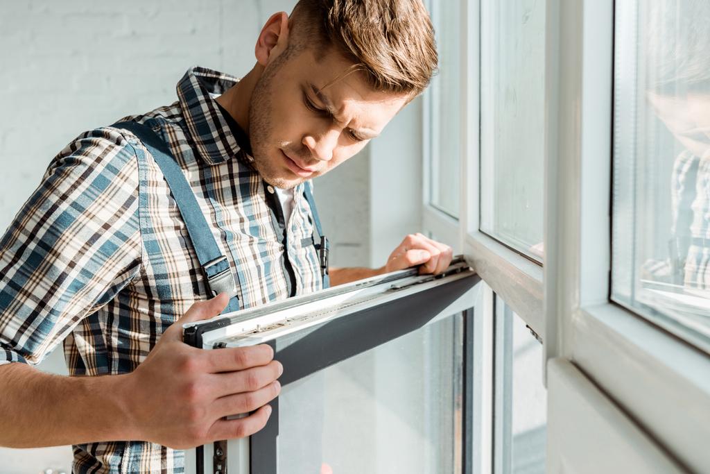 selective focus of handsome installer touching window  - Photo, Image