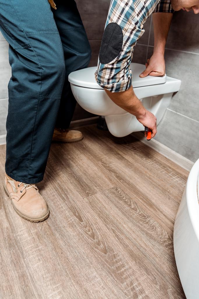 oříznutý pohled na muže instalujícího bílý záchod  - Fotografie, Obrázek