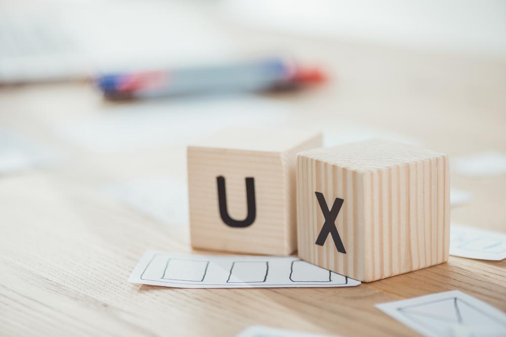 Selectieve focus van houten blokjes met ux letters en webschetsen op tafel - Foto, afbeelding