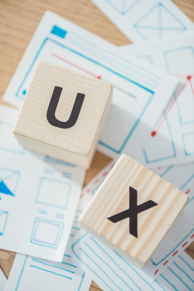 Вид сверху буквы ux на деревянных кубиках с макетом сайта на столе
 - Фото, изображение