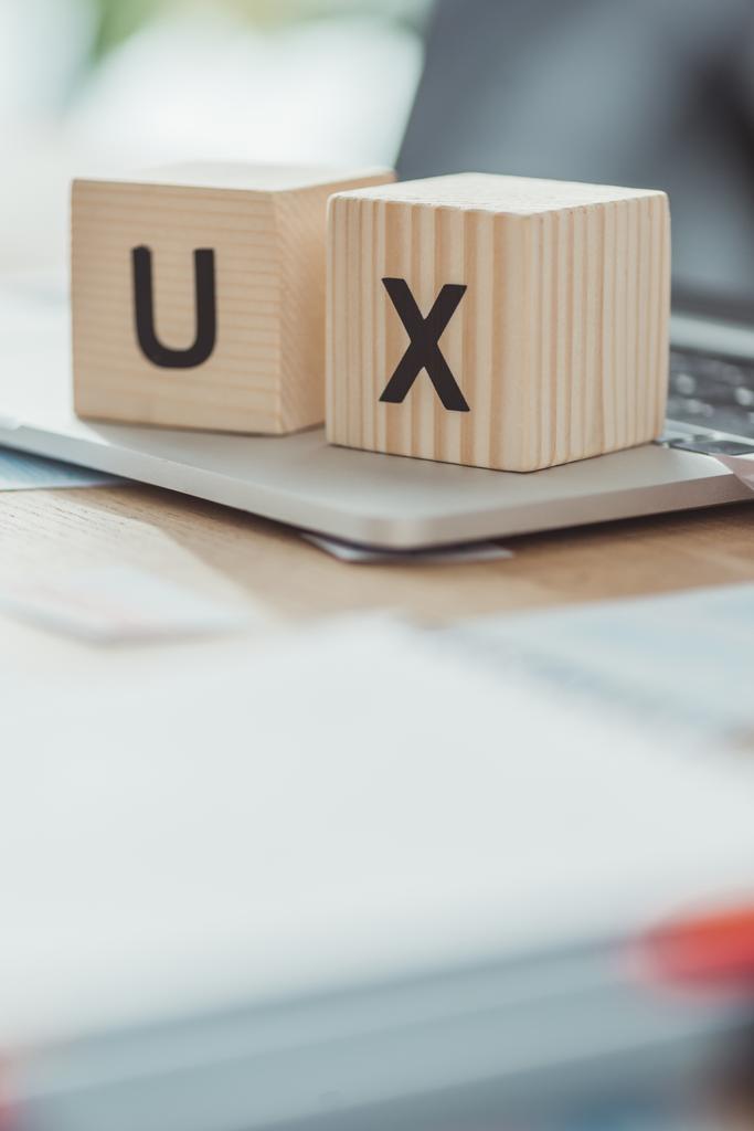 Selektive Fokussierung von Holzwürfeln mit UX-Buchstaben auf Laptop auf Tisch - Foto, Bild