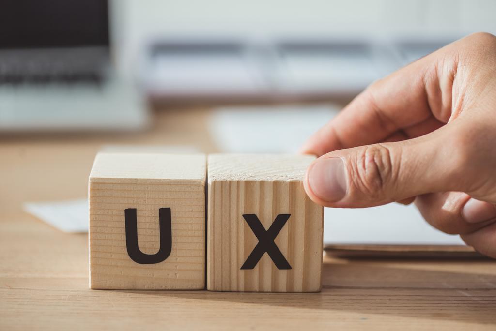 Cropped view of man holding wooden cube with ux letters at wooden table - Photo, Image