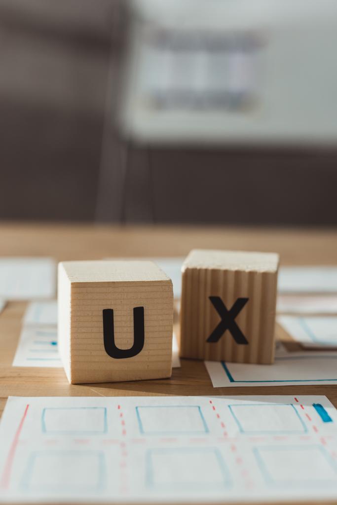 Foco seletivo de cubos com letras ux e layouts de design de experiência do usuário na mesa
 - Foto, Imagem